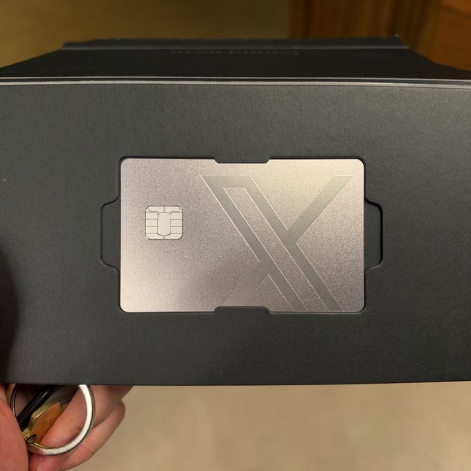 A metallic credit card with a smart chip and an 'X' design rests inside a black presentation box held by a person, likely an Expat Mortgages branded metal card.
