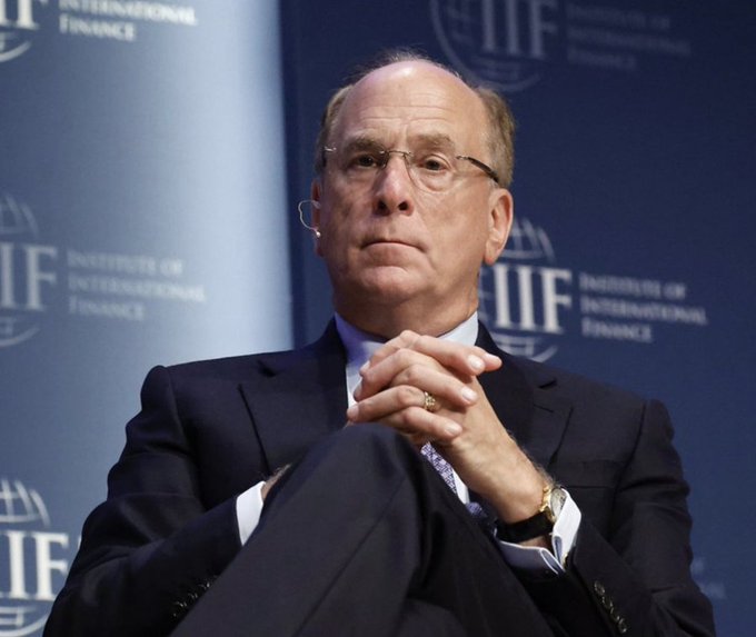Larry Fink, CEO of BlackRock, sits onstage at an Institute of International Finance event, listening with his hands clasped. The post connects his reported expectations of continued investor inflows into Bitcoin to the image of Fink.