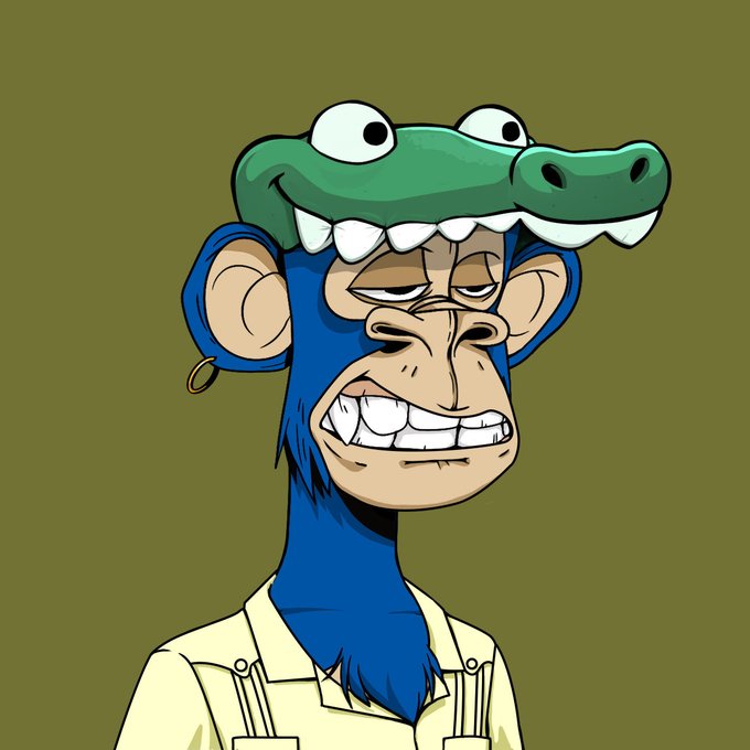 A cartoon illustration of a blue-furred monkey character wearing an alligator/crocodile hat, showing a wide grin and wearing a cream-colored shirt with suspenders.