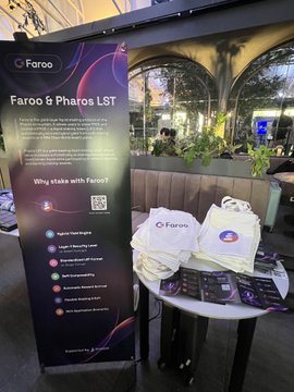 A promotional banner for 'Faroo & Pharos LST' stands next to a table displaying branded merchandise and pamphlets at an event venue.