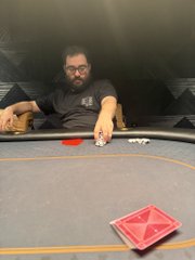 A bearded man with glasses sits at a green felt poker table, pushing chips forward, with a deck of cards visible in the foreground—capturing a moment that mirrors the post's nostalgic reflection on "coins and dreams" and crypto's roots as a speculative, high-stakes game.