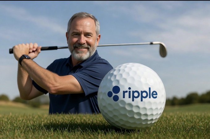A smiling bearded man in a navy polo shirt holding a golf club behind his shoulders, standing behind an oversized golf ball with the 'ripple' cryptocurrency logo printed on it.