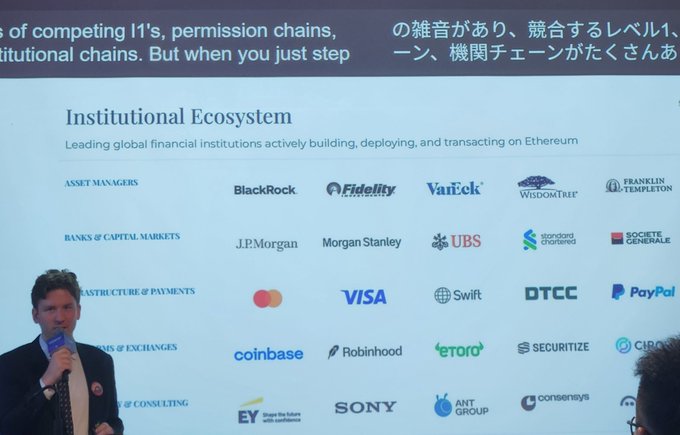 A presenter in a suit stands in front of a presentation slide titled 'Institutional Ecosystem' listing major financial institutions building on Ethereum, including BlackRock, Fidelity, VanEck, BlackRock, J.P.Morgan, Morgan Stanley, UBS, Mastercard, VISA, and Coinbase.