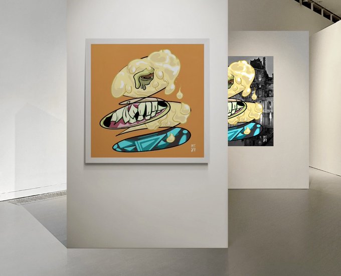 A gallery display features two framed artworks with a cartoon-style design, the first showing floating elements including a disembodied mouth, teeth, and a skateboard on an orange background, while the second depicts a similar character against a black-and-white cityscape.