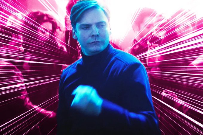 A man in a dark turtleneck stands in a running pose against a vibrant pink and purple neon background with speed lines.