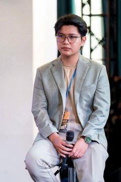 The image features a man wearing glasses, sitting down with his hands clasped together. He appears to be dressed professionally, possibly in a suit or blazer. The background of the image shows a white wall, which contrasts with the gray chair he is seated on. There are also some text elements present in the image that read "What a week for blockchain/web3 enthusiasts in Da Nang! What happened? A LOT + @sqrDAO hosted the 3rd Web3 Builders' Summit (W3BS) and it keeps getting better Da Nang Angel and Venture Summit (DAVAS)", which suggests that there might be an event or gathering related to blockchain technology taking place.