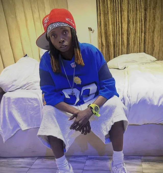 A young man with long dreadlocks wearing a red "Hit Em Up" cap, blue jersey, and a towel sits on a bed, staring contemplatively at the camera. The image illustrates skepticism toward a crypto scam promising to double 300 SOL to 600 SOL, capturing the hesitant, dubious mood of someone weighing whether to trust a too-good-to-be-true offer.