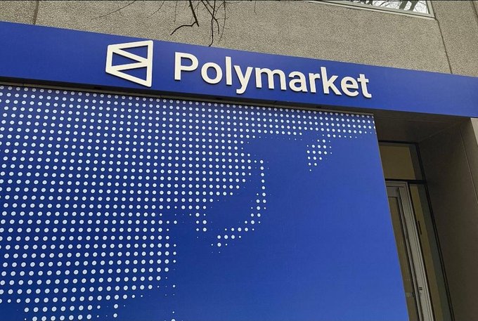 In this image, there's a blue sign with white dots hanging over a building. The text on the sign reads "Polymarket" followed by the numbers "25.7B" indicating that the trading volume was $25.7 billion during March in 2016. Additionally, the post states that people are using Polymarket to trade on information about politics, sports, cryptocurrency, and global events.