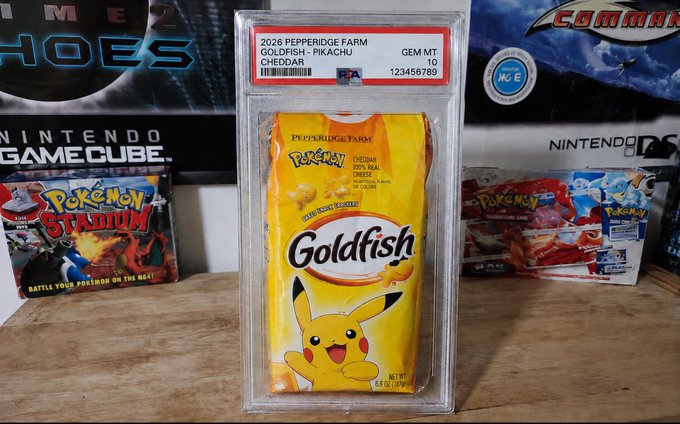 A PSA-graded 10 Goldfish cracker pack (Goldfish • Pikachu) sits encased in its grading slab alongside Pokémon merchandise, humorously receiving the same professional collectible treatment typically reserved for rare trading cards.