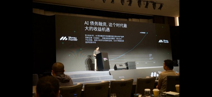 A conference scene shows a speaker at a podium presenting on a large screen displaying Chinese text about AI debt financing opportunities, with a Money Frontier logo and a rising chart line visible, while audience members watch from their seats.
