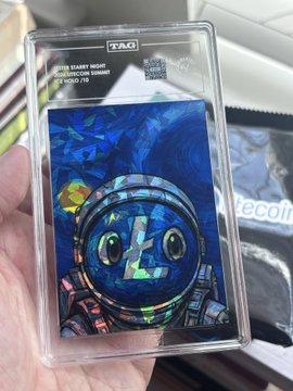 A hand holds a TAG-graded Litecoin "Barry White" Holographic Series #10 trading card with a Midas f9 grade, displayed in its protective slab from the Litecoin Summit Amsterdam 2026 event distributed by the Litecoin Foundation and graded by TAG Grading.