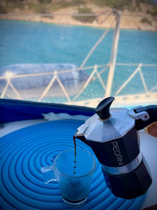 Italian coffee on a boat in a stunning coastal setting—poured from a Pedrini moka pot into a small glass, with turquoise waters and rocky shoreline in the background. The "GM !" post hints at a "Good Morning" greeting, perfect for enjoying a fresh espresso while taking in the morning sea views.