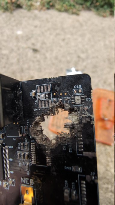 A damaged COLDCARD hardware wallet circuit board with a visible burn hole in the center, surrounded by components labeled C19, U5, R43, J6, and the marking "NEB," illustrating the "Proper COLDCARD disposal (SHOOT HERE)" instruction.