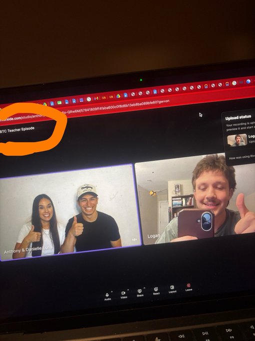 A laptop screen showing a video call interface with multiple participants, including 'Anthony & Danielle Luna' (giving thumbs up) and 'Logan' (holding up his phone), with a YouTube tab URL visible at the top.