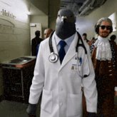 The image features a man dressed as a doctor, wearing a white coat and blue tie, standing next to another person who appears to be dressed like a judge or a lawyer. The background of the image shows a hallway with several people present, including one individual wearing a robe. The caption provided in the image seems to be related to a social media post that includes a reference to a famous quote by a well-known author.

The main focus of the image is on the man dressed as a doctor and his companion who appears to be dressed like a judge or a lawyer, both standing together in what seems to be an indoor setting with people present around them. The caption provided in the image provides context about the social media post that includes a reference to a famous quote by a well-known author.