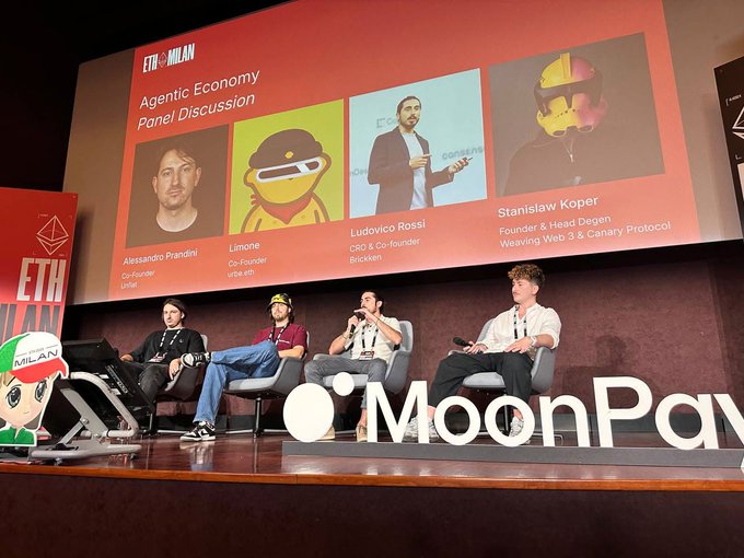 The image shows a group of four people sitting around a stage, likely at an event or conference related to the Agentic Economy. They are engaged in a discussion about the shift from theory to infrastructure when it comes to agentic finance. The main speaker is addressing the crowd and discussing the challenges surrounding authorization for autonomous agents.