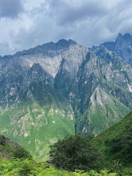 Dramatic peaks of a lush mountain valley rise beneath a cloudy sky, with greenery blanketing the steep slopes. The image complements the post by humorously contrasting the fast-paced crypto trading lifestyle on Hyperliquid with waking up to a serene, breathtaking natural view.