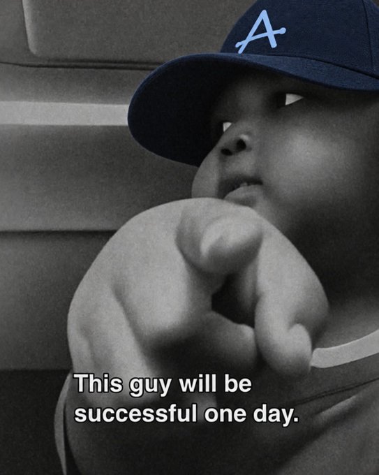 A black-and-white photo shows a baby wearing a blue cap with a stylized 'A' pointing forward, with caption text reading 'This guy will be successful one day.'
