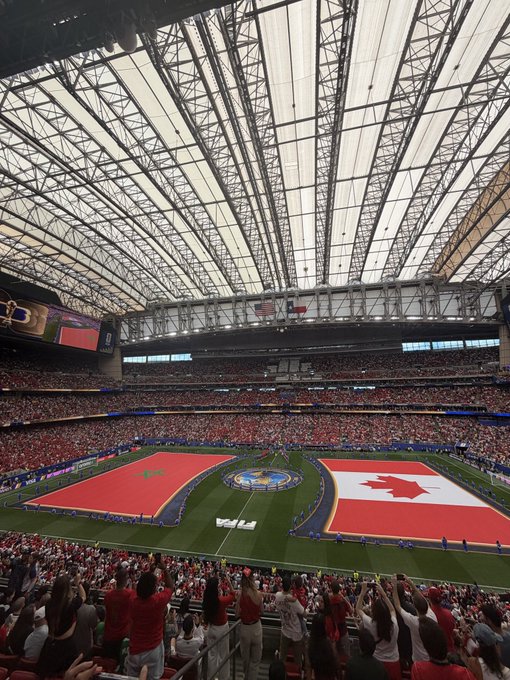 A packed indoor stadium features large Canadian and American flags draped across the field with a "WTA" logo visible, while a crowd of fans in red cheers from the stands — likely capturing the moment before or after a tennis match, complementing the post's thanks to @ZoomexOfficial for the hospitality experience.