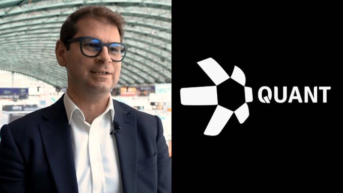 A man in glasses and a suit speaking in what appears to be an interview setting, with the 'QUANT' logo displayed on a black background beside him.