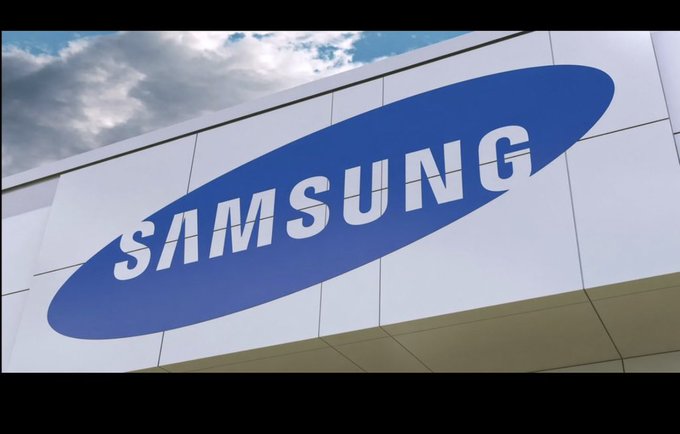 The image displays the Samsung logo prominently featured on the exterior of a building against a partly cloudy sky, directly representing the company mentioned in the post about Samsung's announcement at Galaxy Unpacked to integrate native stablecoin support into Samsung Wallet.