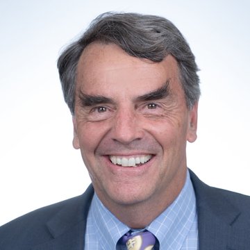 A professional headshot of a smiling middle-aged man with gray hair, wearing a dark suit, light blue checkered shirt, and patterned tie, likely Tim Draper, whose bullish prediction about Bitcoin reaching $250,000 by mid-2028 accompanies this image.