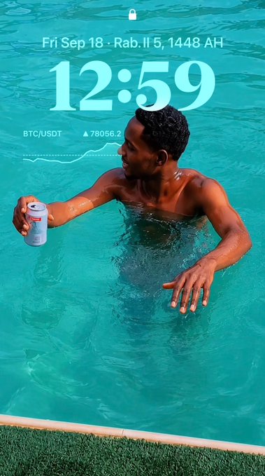 A lock screen displaying 'Fri Sep 18 · Rab. II 5, 1448 AH' and the time '12:59' over an image of a shirtless Black man standing in a turquoise pool holding a silver can.
