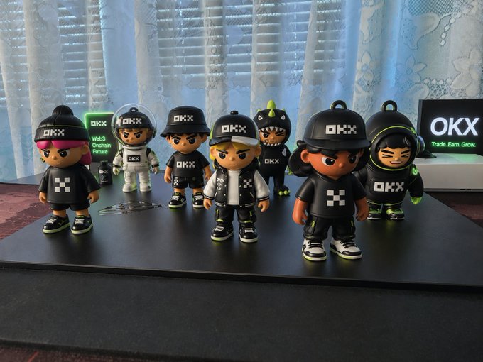 A collection of OKX-branded collectible figures stand ready, representing the "OKX army" in anticipation of the "battlefield." The image directly visualizes the post's metaphor of a growing community ready to face market conditions.