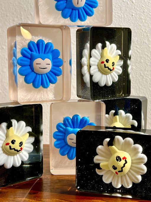 A collection of decorative resin blocks featuring blue and white flower designs with cute cartoon faces embedded inside, arranged on a wooden surface.
