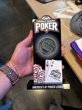 A hand holding a 'World Poker Tour' promotional pamphlet for the Triton Fall Edition at the table.