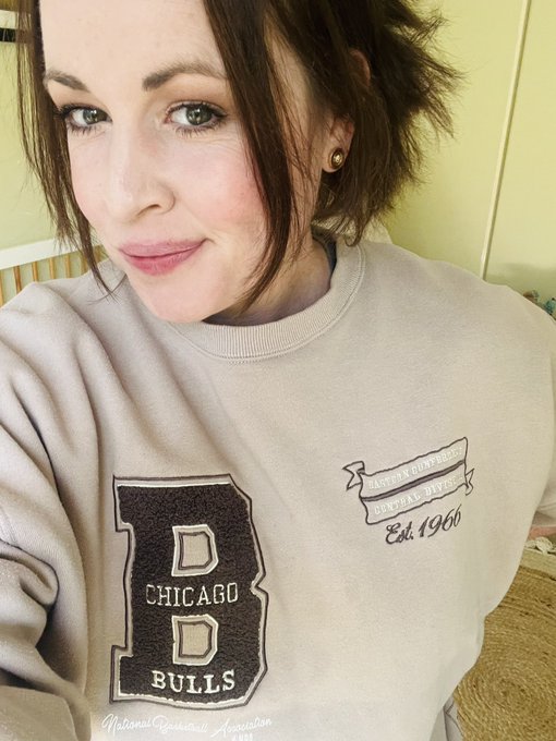 A woman taking a selfie wearing a beige Chicago Bulls sweatshirt with 'B' logo and 'Est 1966' text.