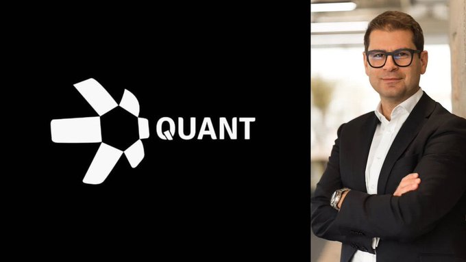 A promotional image displays the 'QUANT' logo with a star-like symbol on a black background next to a portrait of a man in glasses and a black suit with his arms crossed.