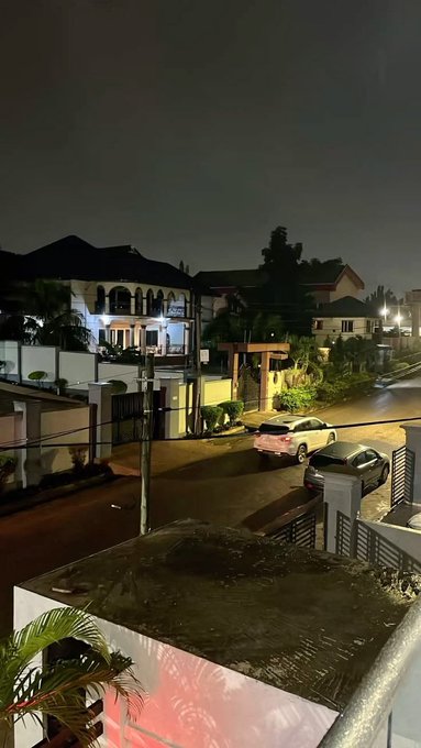 A nighttime view of a quiet residential street with parked cars and illuminated houses, captured from an elevated vantage point, likely a balcony or rooftop. The scene complements the post's reflective tone, suggesting a peaceful end to a busy day before signing off until tomorrow.