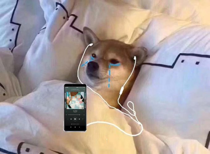A humorous edited photo of a Shiba Inu dog lying in bed with drawn-on blue tear lines and white earphones plugged into a smartphone displaying a music player.