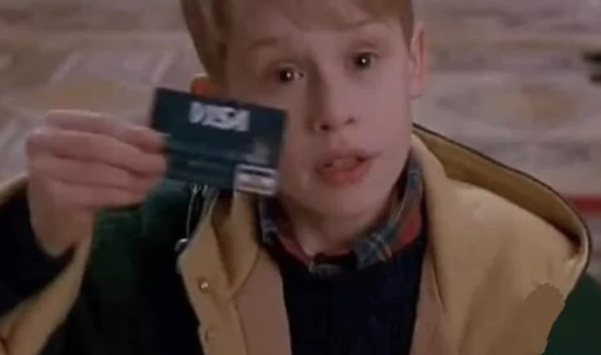 A young red-haired boy excitedly holding up a VISA credit card, a classic scene from the movie Home Alone.