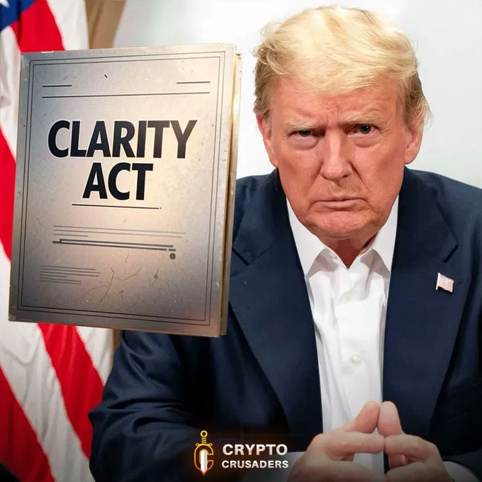 The image shows a man sitting at a table, posing as if he works for or is part of a political campaign related to cryptocurrencies. A sign behind him displays the phrase "CLARITY ACT". The man appears to be wearing a suit and tie. There is another person in the background who seems to be working with the political campaign.