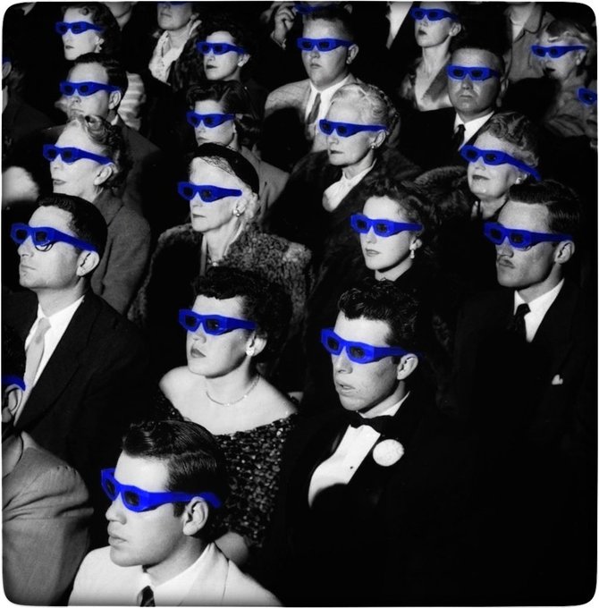 A vintage black-and-white photo of a movie theater audience all wearing blue 3D glasses.