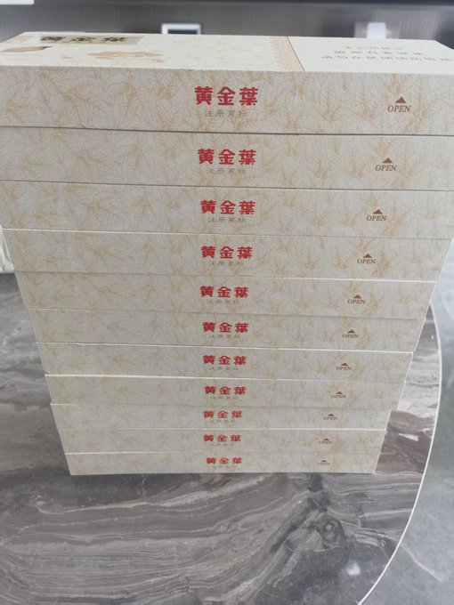 A stack of ten white boxes labeled '黃金撻' (Golden Tart) with 'OPEN' printed on the side, sitting on a marble surface.