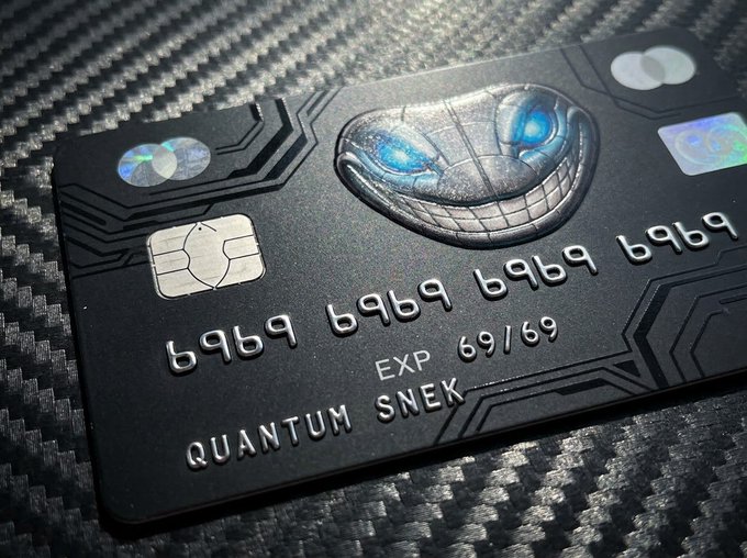 A black metal debit card featuring an embossed metallic snake design, labeled 'QUANTUM SNEK' and 'EXP 69/69', with the card number '6969 6969 6969 6969' sits on a carbon fiber surface.