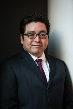 The image features a man wearing glasses and a suit standing against a wall with his hands at his sides. He appears to be posing for a photo, possibly for a company's promotional material or website. The text "Tom Lee'S company 'BitMine' has made a big move by purchasing 126,971 $ETH" is visible in the image, which suggests that the man might be associated with Bit Mine, an online marketplace where people can buy and sell Bitcoins. This could imply that the man's role at the company involves managing or promoting Bitcoin transactions on the platform.