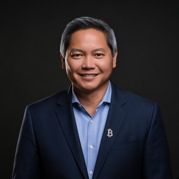 A professional headshot of a smiling man wearing a dark blazer over a blue button-down shirt, who appears to be Phong Le, the CEO of Strategy (formerly MicroStrategy), whose lapel pin and the accompanying post reference the company's plan to resume purchasing Bitcoin after a seven-week pause.