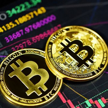 Two gold Bitcoin tokens rest atop a digital trading chart displaying fluctuating candlestick patterns and price figures like "34221" and "33687," visually representing the rarity highlighted in the statistic that only about 825,000 people worldwide own a whole Bitcoin.