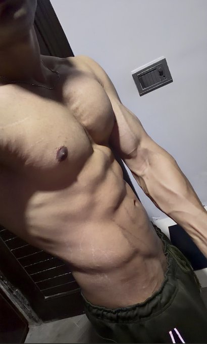 A close-up photo of a shirtless man flexing, showing highly defined abdominal and chest muscles.