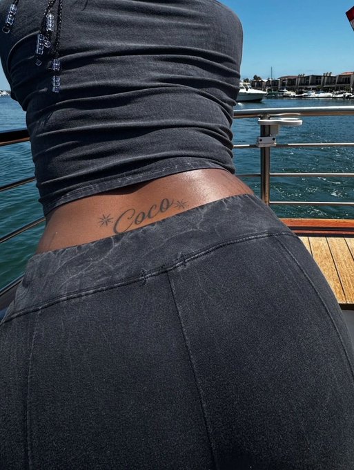 A photograph taken from behind shows a person in black athletic wear standing by a marina, displaying a 'Coco' tattoo with star accents on their lower back.