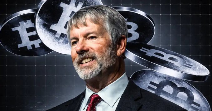 A photograph of Michael Saylor, the MicroStrategy executive, smiling in a suit with Bitcoin coins floating in the background of the image.