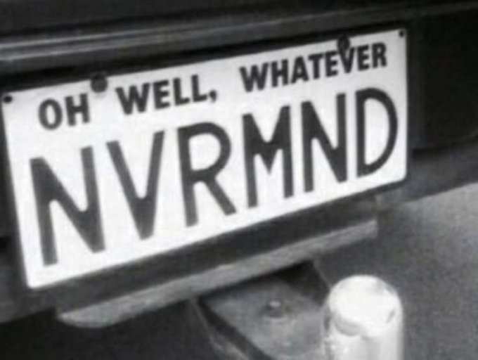 A black and white photo of a vehicle's license plate that reads 'OH WELL, WHATEVER' on top and 'NVRMND' (Nevermind) as the main identifier.