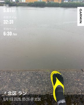 The image shows a person's foot wearing yellow flip flops, standing on a stone wall or ledge by a body of water. The photo appears to be taken during the day under cloudy skies, with the person's feet visible as the main subject in the frame. The caption "おはよー 今朝もリカバリー #STEPN" suggests that this image might have been captured by a photographer who is interested in capturing unique or interesting subjects for their photos.