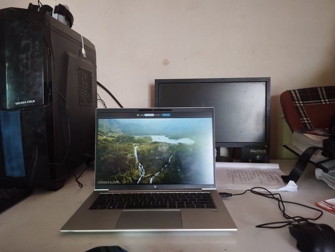A laptop displaying a scenic waterfall wallpaper sits on a desk next to a computer tower labeled 'GOLDEN FIELD' and an external monitor.