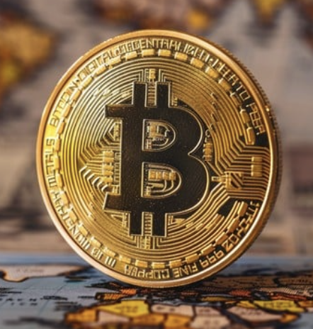 A close-up of a gold Bitcoin physical coin featuring the iconic "₿" symbol and inscribed with "BITCOIN DIGITAL DECENTRALIZED PEER TO PEER" and "VIRES IN NUMERIS FINE COPPER," set against a blurred background of currency.

The image mirrors the post's narrative of Bitcoin's evolution from a "dragon-slaying youth" to the "dragon" itself—the polished gold coin, now an icon of wealth and power, embodies how the once-revolutionary challenger has become the very behemoth it sought to overthrow.