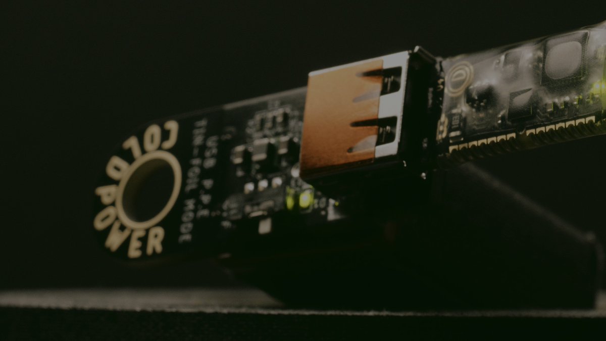 The image features a close-up view of a USB cable with a brown connector at one end and a black circuit board with a white label that says "Opendime" on it, indicating that this was released ten years ago. The USB cable is connected to a small device, possibly a computer or electronic gadget, which has a black surface underneath it. There are also two resistors visible in the image, one of them being a gold color and the other being silver.